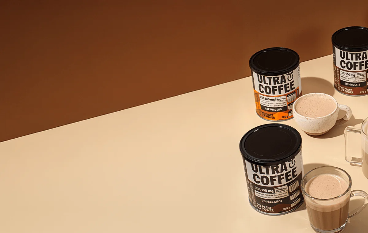 Latas de Ultracoffee nos cinco sabores ao lado de xícaras de café.